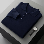 Folded navy blue polo shirt with a watch on a gray surface