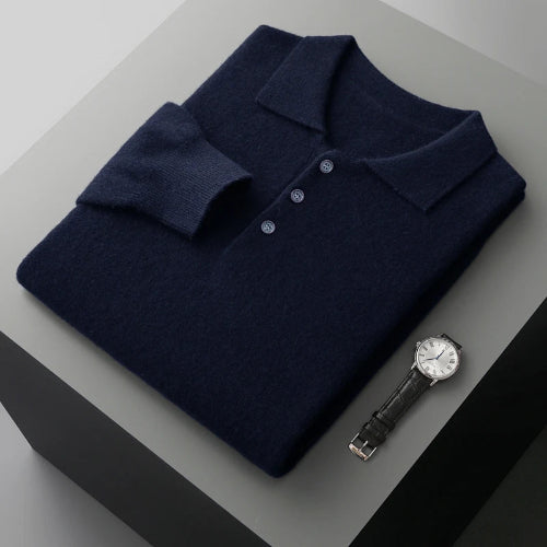 Folded navy blue polo shirt with a watch on a gray surface