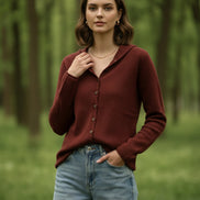 Person wearing a brown button-up sweater with a blurred background