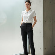 White blouse with black buttons on a hanger against a white background