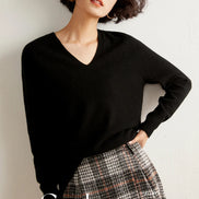 Woman wearing a black cashmere sweater with a plain background