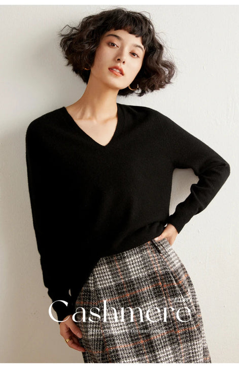 Woman wearing a black cashmere sweater with a plain background