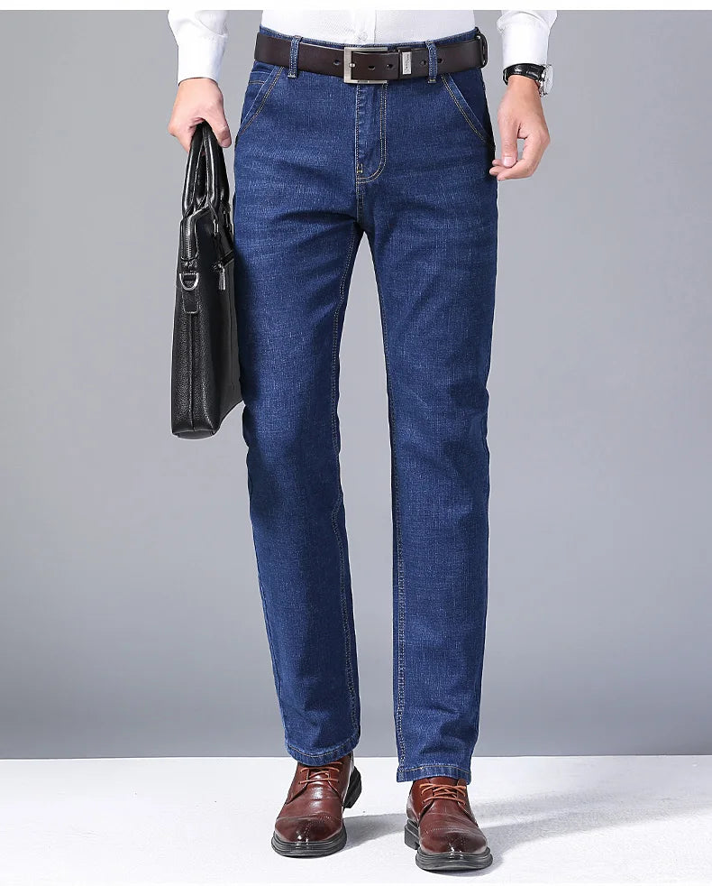 Person wearing blue jeans holding a black leather briefcase on a gray background