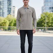 Gray polo shirt with a brand logo on a hanger against a blurred clothing rack background