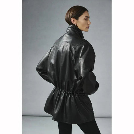 Rear three-quarter view of a woman wearing a black faux leather jacket with a raised collar and gathered waist