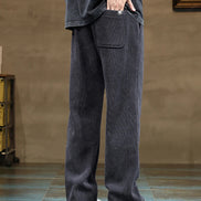 Person wearing dark gray wide-leg pants with a plain background