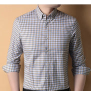 Person wearing a checkered shirt with rolled-up sleeves against a beige background
