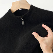 Black sweater on a hanger with a hand touching the fabric