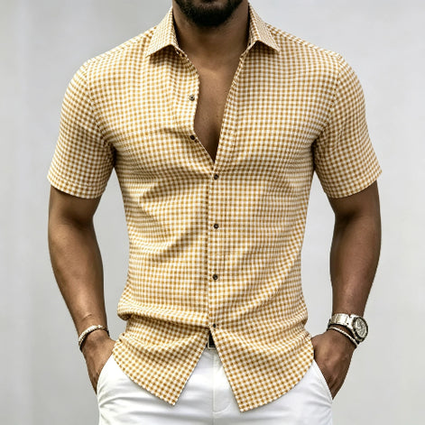A man wearing a short-sleeve button-up shirt with a yellow and white gingham check pattern, paired with white pants, 