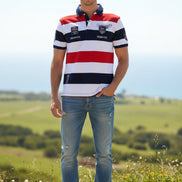 A short-sleeve striped polo shirt with horizontal bands of white, red, and navy blue. The shirt features a navy blue collar, a navy blue chest stripe, and multiple embroidered and printed