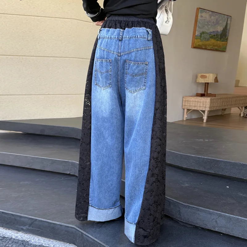 A person wearing wide-leg jeans with a light blue denim body and black lace side panels, shown from the back in an indoor setting with steps and a bench in the background.