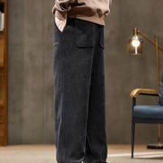 Person wearing dark pants and a beige sweater in a room with a lamp and chair.