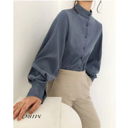 Person wearing a blue shirt and beige pants against a white background