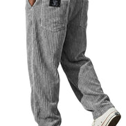Gray and white vertically striped corduroy pants shown on a model from the back, paired with a white t-shirt and white low-top sneakers.
