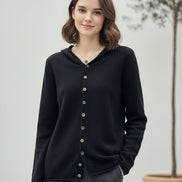 Person wearing a dark cardigan taking a mirror selfie in a clothing store.