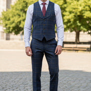 Blue checkered vest with a red tie on a mannequin against a beige curtain background