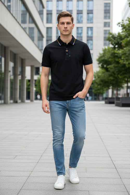 Black polo shirt with a brand logo held by a hand in a clothing store.