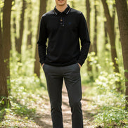 Black long-sleeve polo shirt on a hanger against a gray background