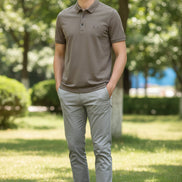 Brown polo shirt in a black box with a watch on a dark surface