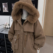 A brown hooded parka jacket with a large fluffy faux-fur trimmed hood, displayed on a mannequin in an indoor boutique setting.