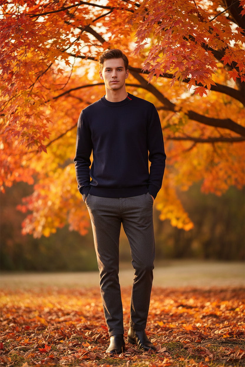 Dark blue sweater with red and green accents in a box, accompanied by a black watch on a dark surface.