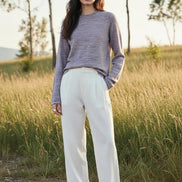 A woman wearing a textured knit long-sleeve sweater in a heathered dusty lavender-gray color, 