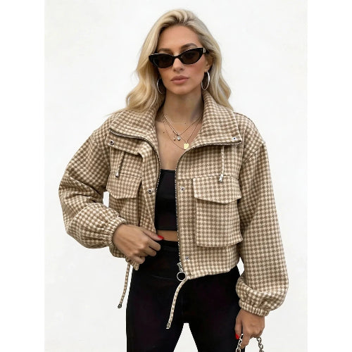 Woman wearing a beige and cream checked utility jacket with chest flap pockets, a ring-pull zipper and drawcord hem over a black top and trousers