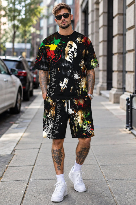 A man walking on a city sidewalk wearing a matching black graphic t-shirt and shorts set with a Bob Marley 