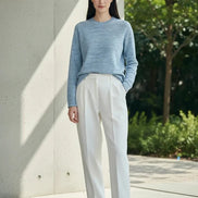 A woman wearing a light blue heathered knit long-sleeve sweater, shown 