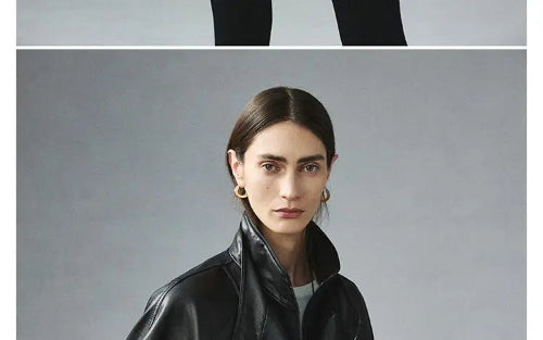 Close-up of a woman wearing a black faux leather jacket with a raised collar over a white top against a gray background⠋