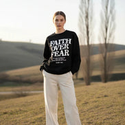 Black sweatshirt with 'Faith Over Fear' text on a wooden background