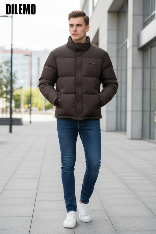 A dark brown puffer jacket with a high collar and snap-button front, shown on a hanger with a hand holding the lower right side. 