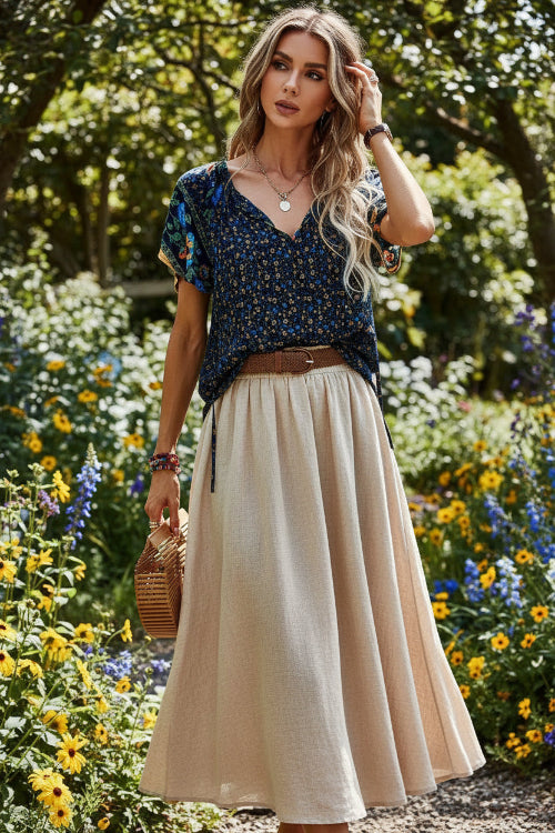 Woman wearing a floral top and denim shorts, holding a straw bag.