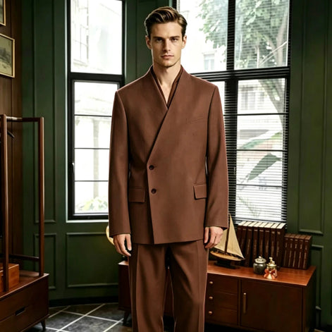 A man wearing a brown double-breasted suit with a shawl collar stands in a vintage-style room with dark green walls, large windows, and wooden furniture.