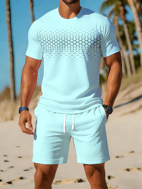 A man wearing a light blue matching swim set consisting of a short-sleeve t-shirt with a black geometric pattern across the chest and matching drawstring shorts, 