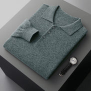 Green sweater with buttons on a gray surface next to a watch