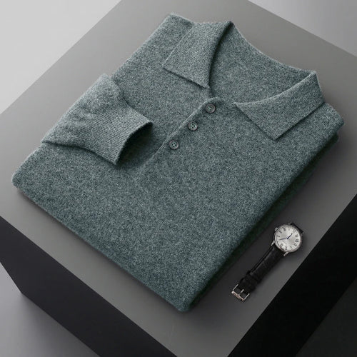 Green sweater with buttons on a gray surface next to a watch
