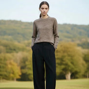 A woman wearing a brown and beige heathered knit long-sleeve sweater with a crew neck, paired with a black skirt.