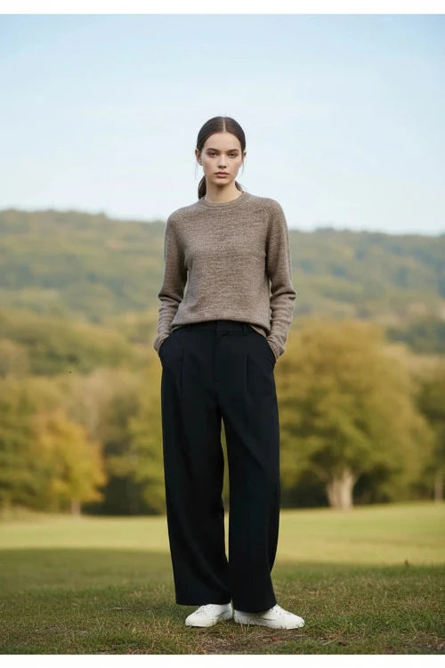 A woman wearing a brown and beige heathered knit long-sleeve sweater with a crew neck, paired with a black skirt.
