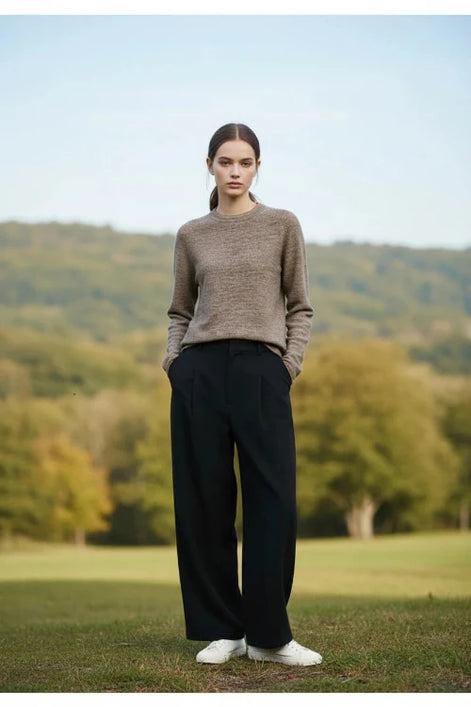 A woman wearing a brown and beige heathered knit long-sleeve sweater with a crew neck, paired with a black skirt.