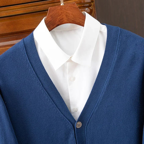 Blue cardigan over a white shirt on a wooden hanger against a wooden background