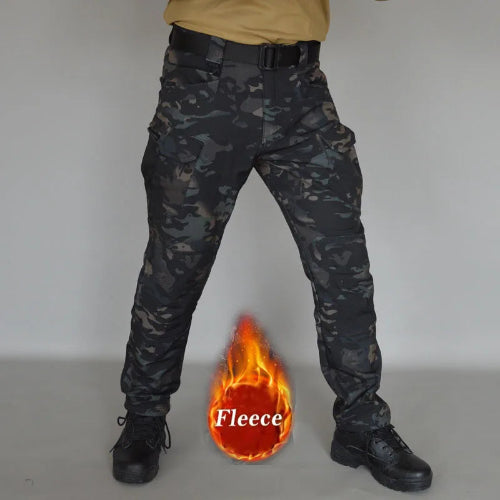Front view of a model wearing dark camouflage cargo pants with a black belt and black lace-up boots, alongside a fleece label graphic against a gray background.
