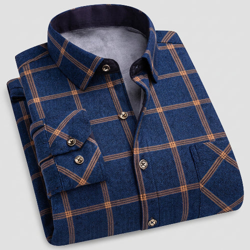 A folded men's button-up shirt in dark blue with a tan plaid pattern, shown on a light gray background 