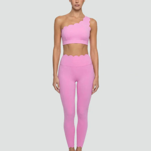 Person wearing a pink one-shoulder top and leggings on a light gray background