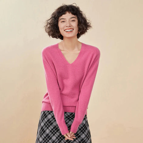 Woman wearing a pink sweater and plaid skirt against a beige background