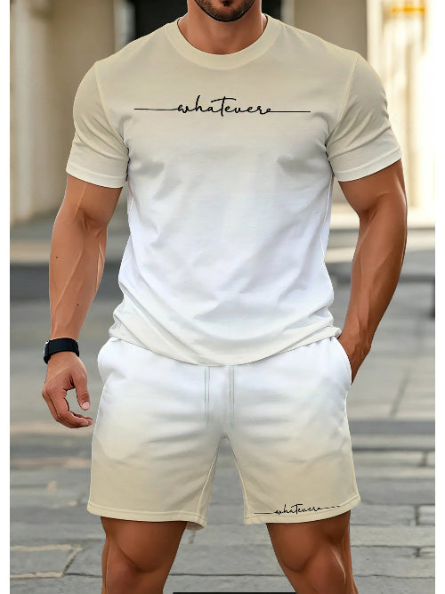 A man wearing a matching beige/cream two-piece lounge set consisting of a short-sleeve crewneck t-shirt and shorts, both featuring the word 'whatevers' printed in black script 