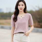 Person wearing a pink textured sweater with a blurred outdoor background
