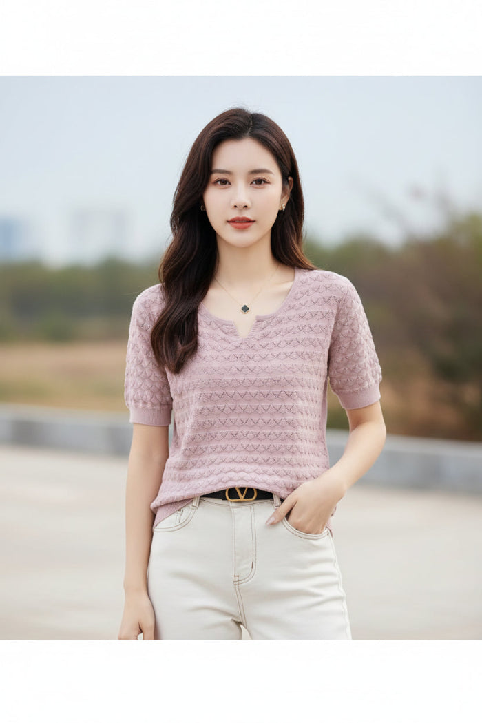 Person wearing a pink textured sweater with a blurred outdoor background