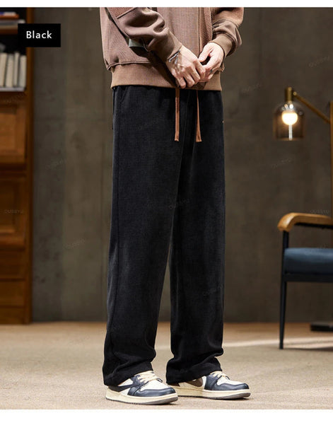 Person wearing black pants and a brown sweater in a room with a lamp and chair.