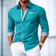 Man wearing a teal button-up shirt with light blue collar and cuffs, white pants, and a watch on a blurred background.